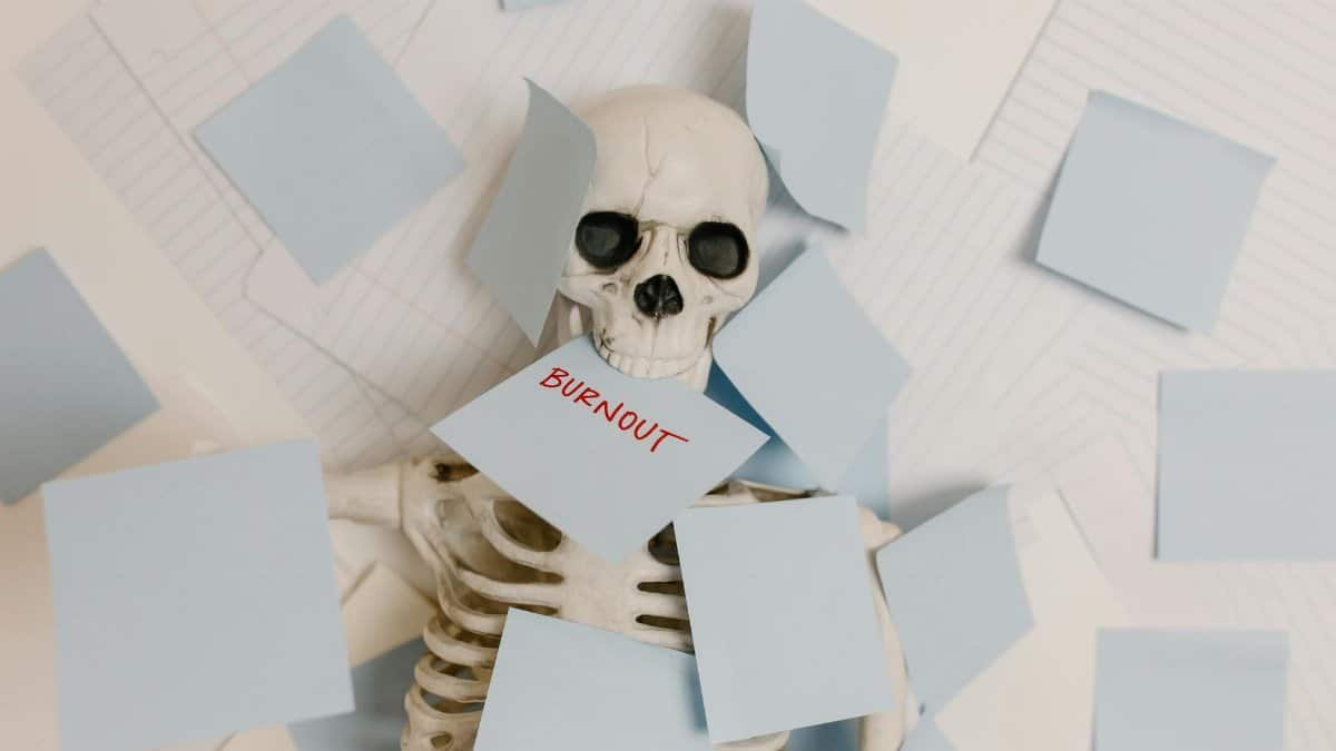A skeleton covered in sticky notes with 'burnout' on one, symbolizing work stress and exhaustion.