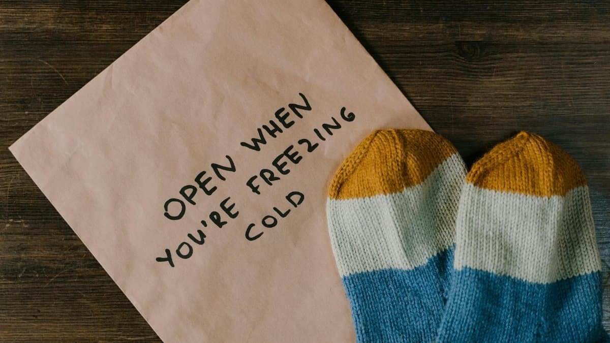 Warm winter gift set with handwritten note and colorful socks on wooden surface.