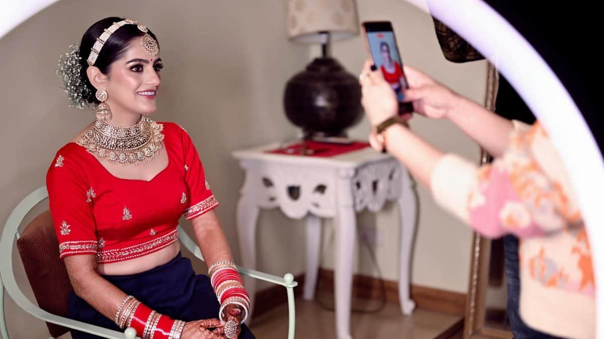 A beautiful bride in traditional Indian attire getting her photo taken indoors. Vibrant and elegant.