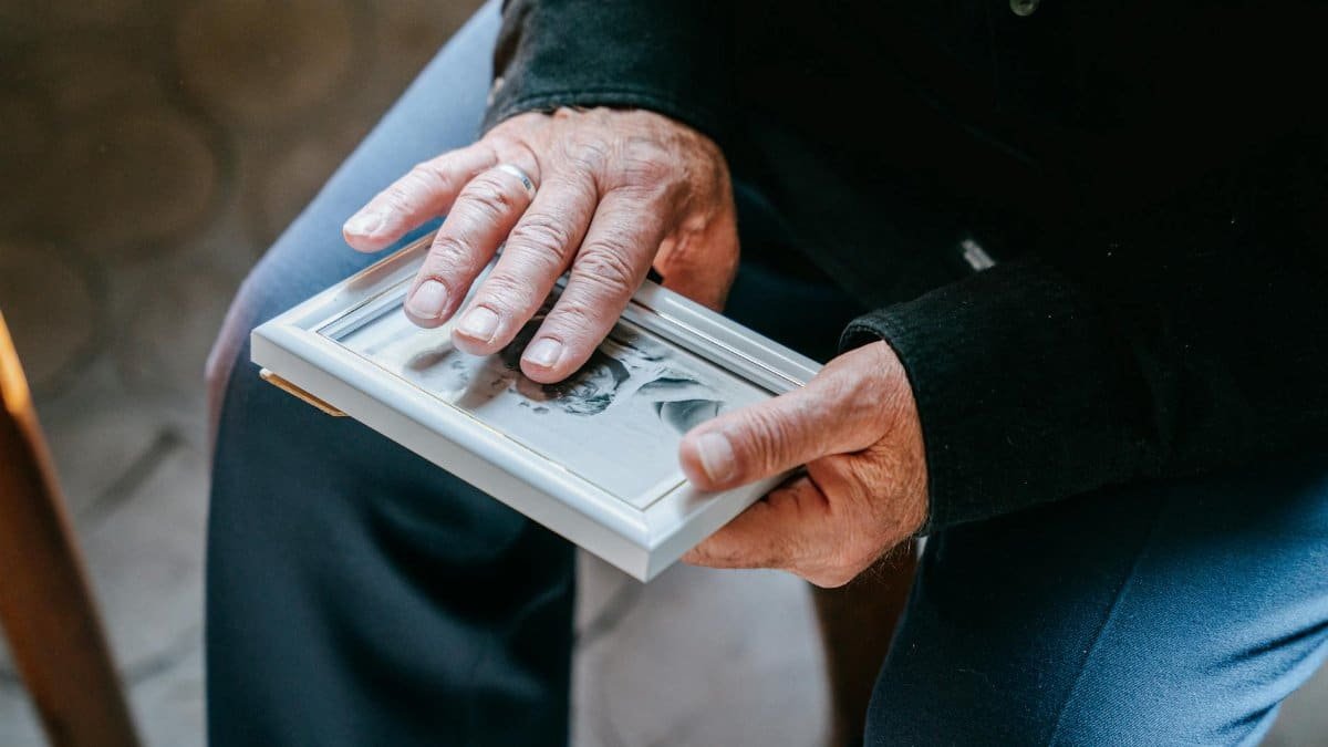 Close-up of elderly hands holding a framed photograph, reflecting nostalgia and emotion.