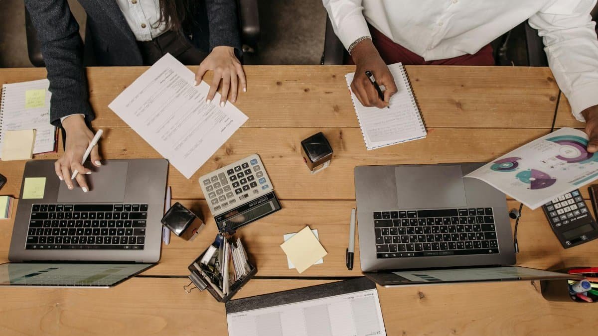 High-angle view of professionals working collaboratively with laptops and documents in an office.