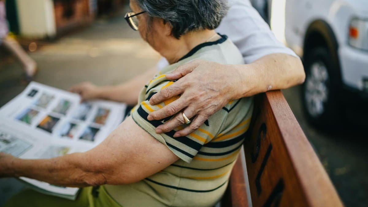 Heartwarming moment with elderly couple reading together while sitting on a bench outdoors.