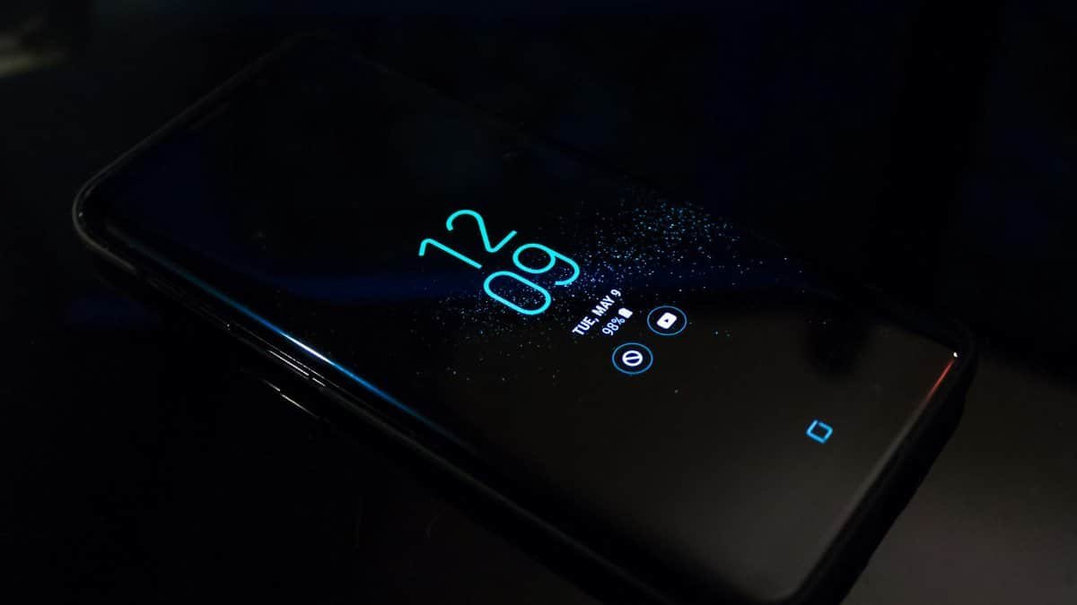 Close-up of a smartphone in the dark displaying digital clock and notifications.