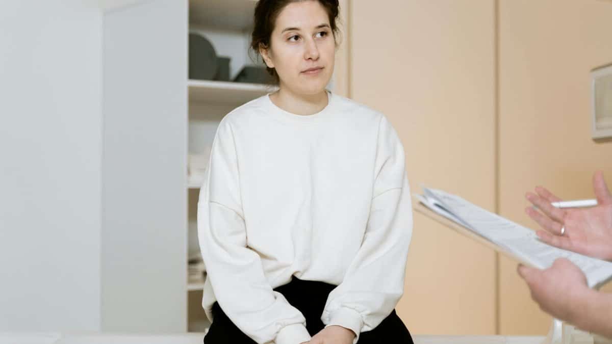 Adult woman sitting attentively during a medical consultation inside a clinic.