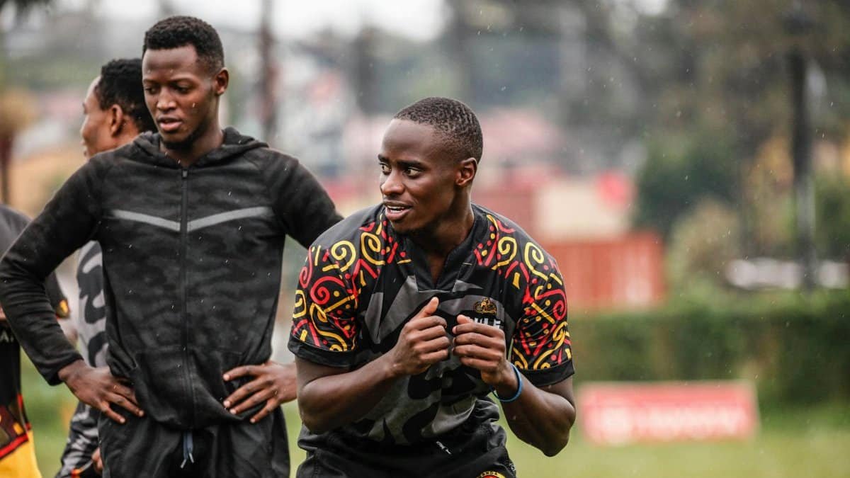 Smiling African athletes in vibrant jerseys have a team practice outdoors.