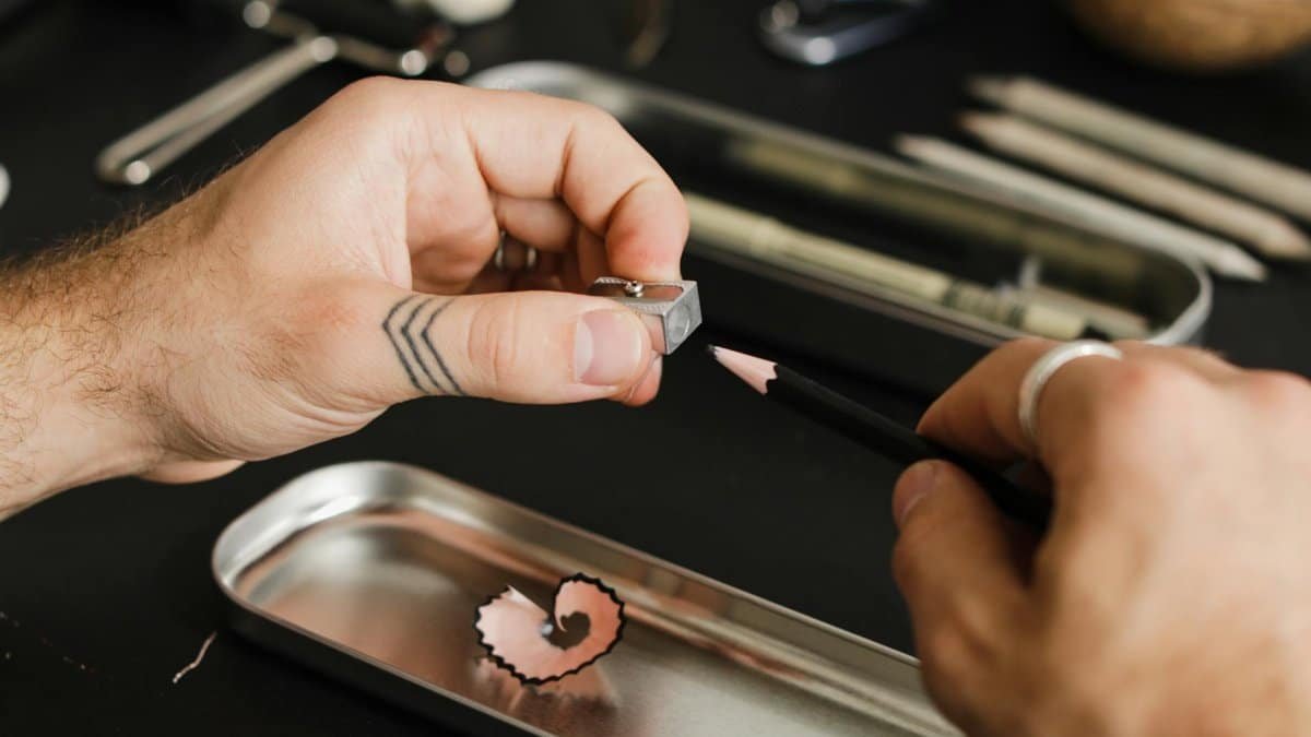 Close-up of hands sharpening a pencil with a manual sharpener. Ideal for educational themes.