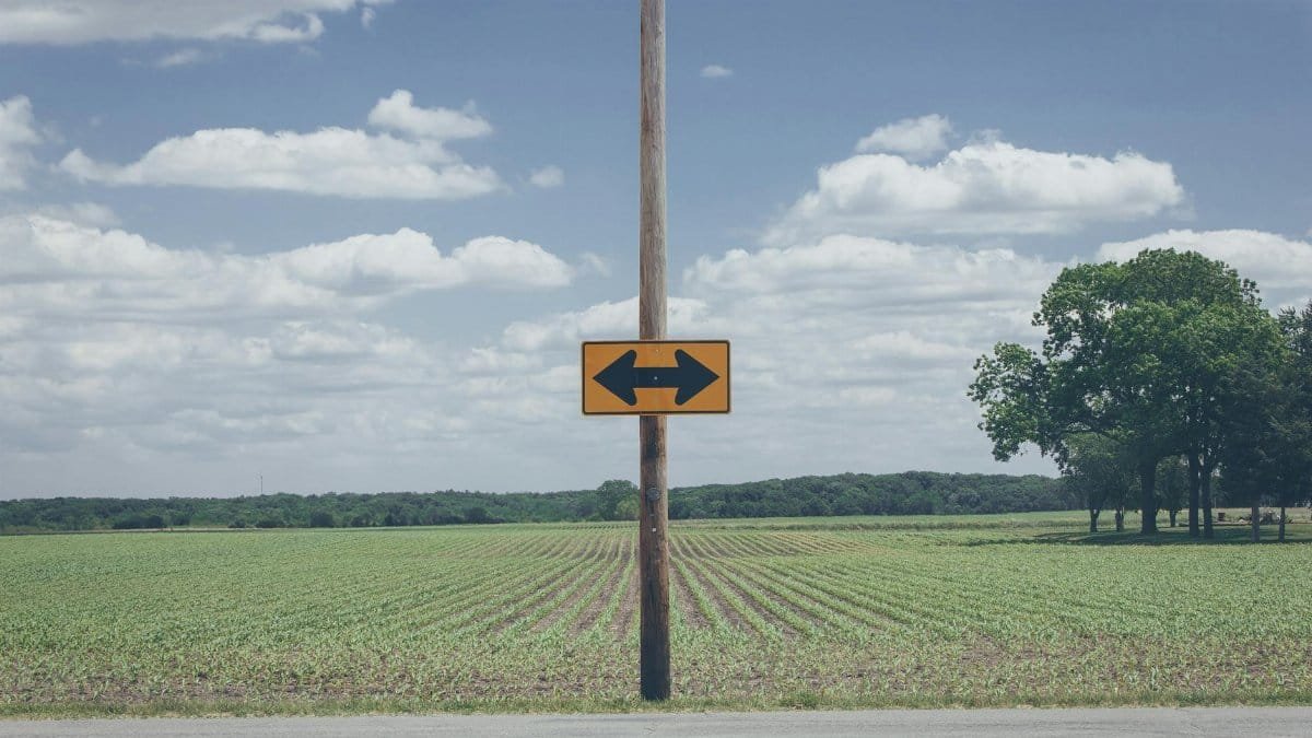 Scenic rural road sign on farmland with clear blue sky and clouds.