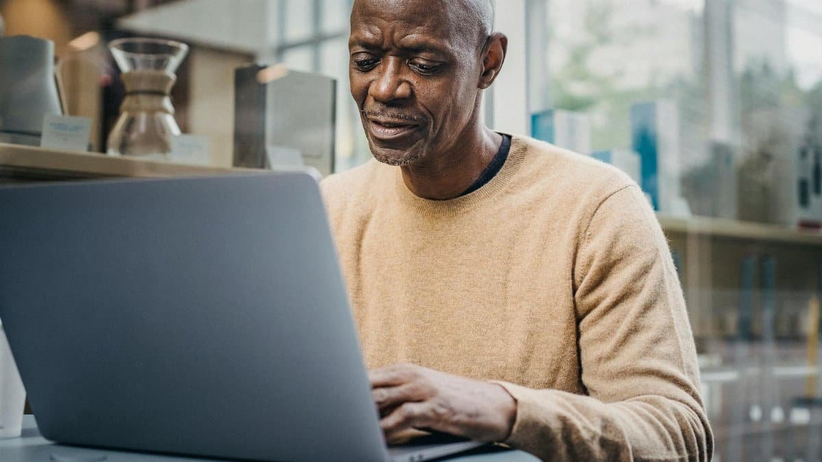 Mature man concentrating on his work using a laptop in an elegant city café.