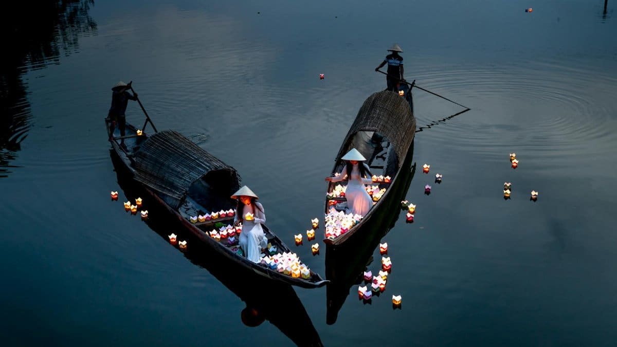 Serene evening scene with traditional boats and lantern-lit women on a tranquil canal.