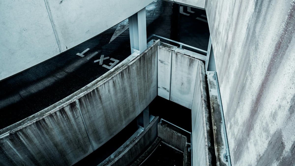 High-angle view of a spiral concrete parking structure with visible exit marking.