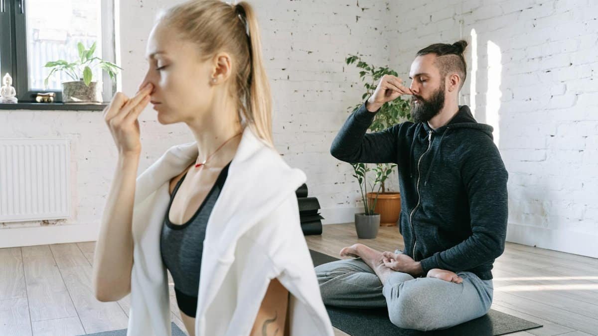 A man and woman practicing mindful yoga and breathing exercises in a serene indoor setting.