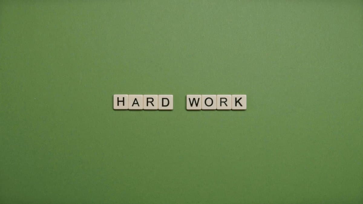 Tiles spelling 'hard work' on a green background symbolizing diligence and effort.