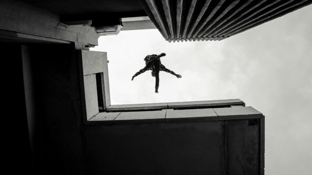 Silhouette of a person performing a parkour jump between buildings in Cape Town, South Africa.