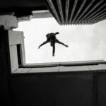 Silhouette of a person performing a parkour jump between buildings in Cape Town, South Africa.