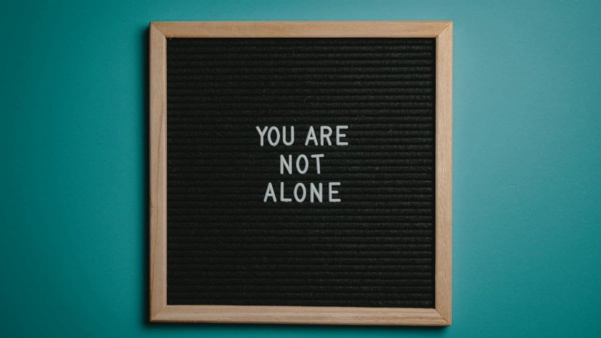 A wooden letter board displays a motivational message against a teal background.