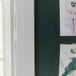 Two artistic posters with inspiring messages displayed on a dark green wall.