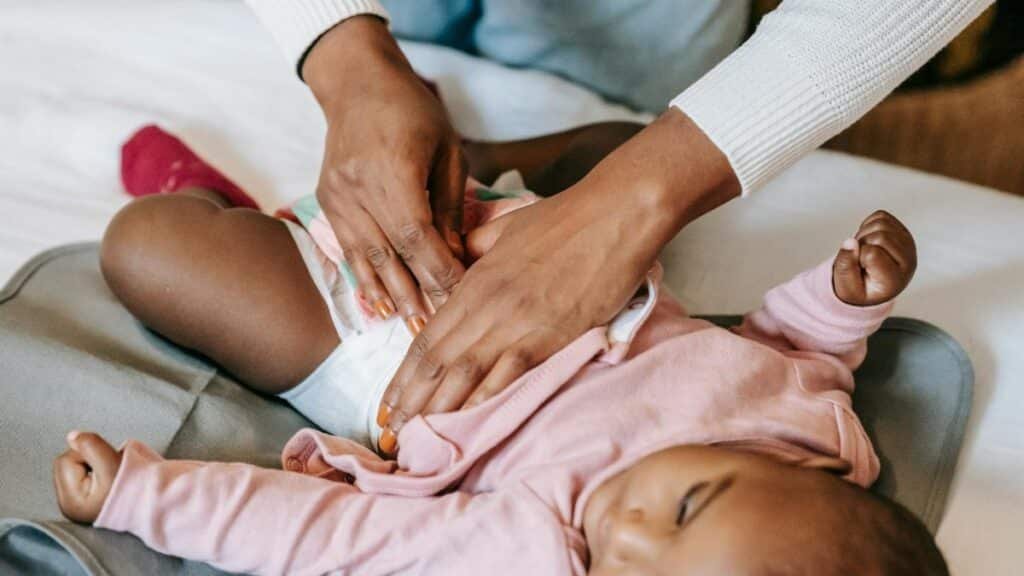 A caregiver gently changing a baby's diaper indoors, showcasing love and care.