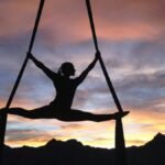 Silhouette of a woman practicing aerial yoga against a vibrant sunset sky in Las Vegas.