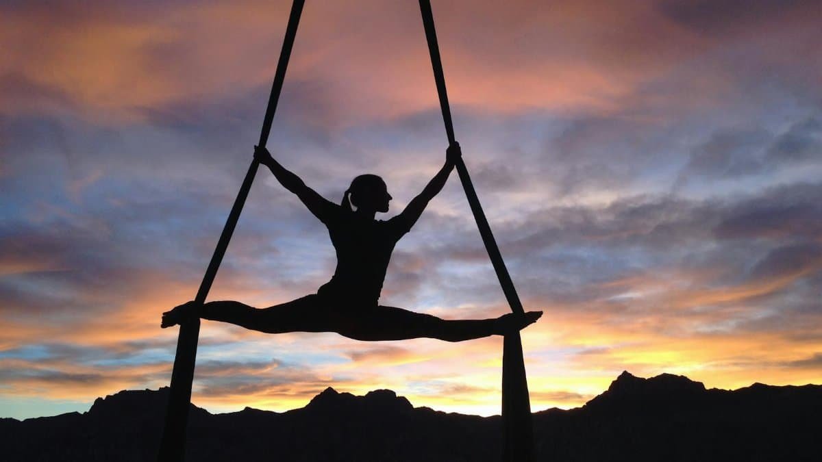 Silhouette of a woman practicing aerial yoga against a vibrant sunset sky in Las Vegas.