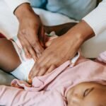 A caregiver gently changing a baby's diaper indoors, showcasing love and care.