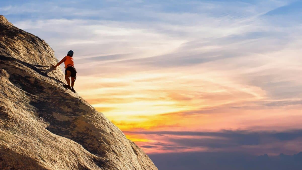 Climber conquers rock face at sunset, embracing the thrill and challenge.