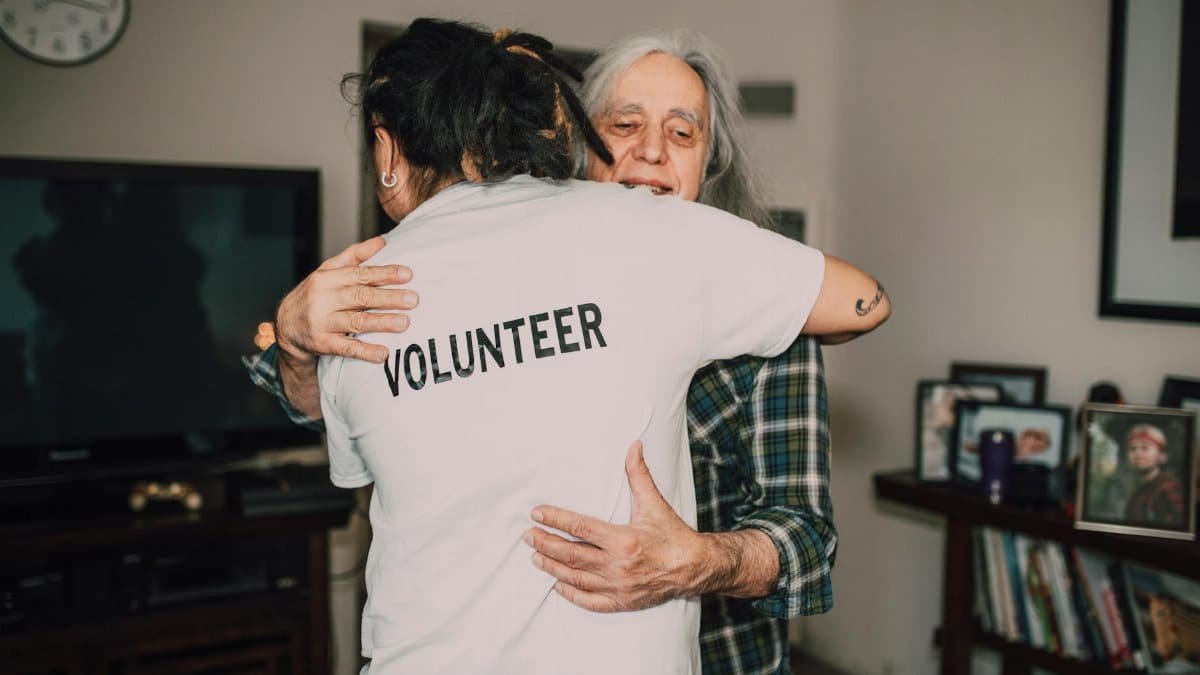 A volunteer embraces a senior woman in a heartfelt moment of support and love.