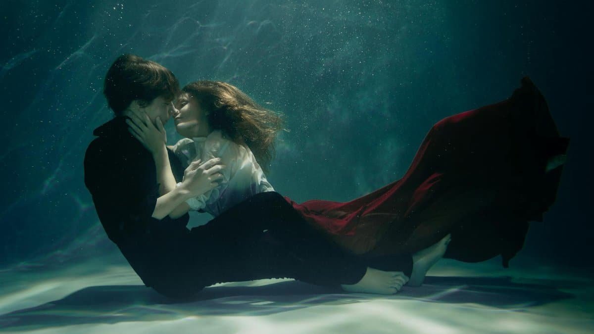 A couple embraces passionately underwater, creating a dreamy and romantic scene.