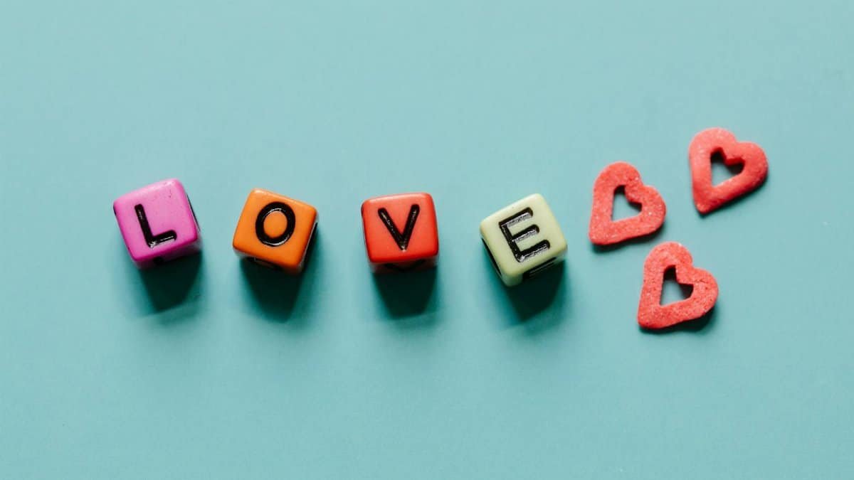 Colorful letter blocks spelling 'LOVE' with red heart shapes on a blue surface, playful and romantic.