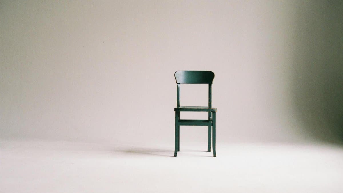 A single black chair in a minimalistic studio setting with a neutral backdrop.