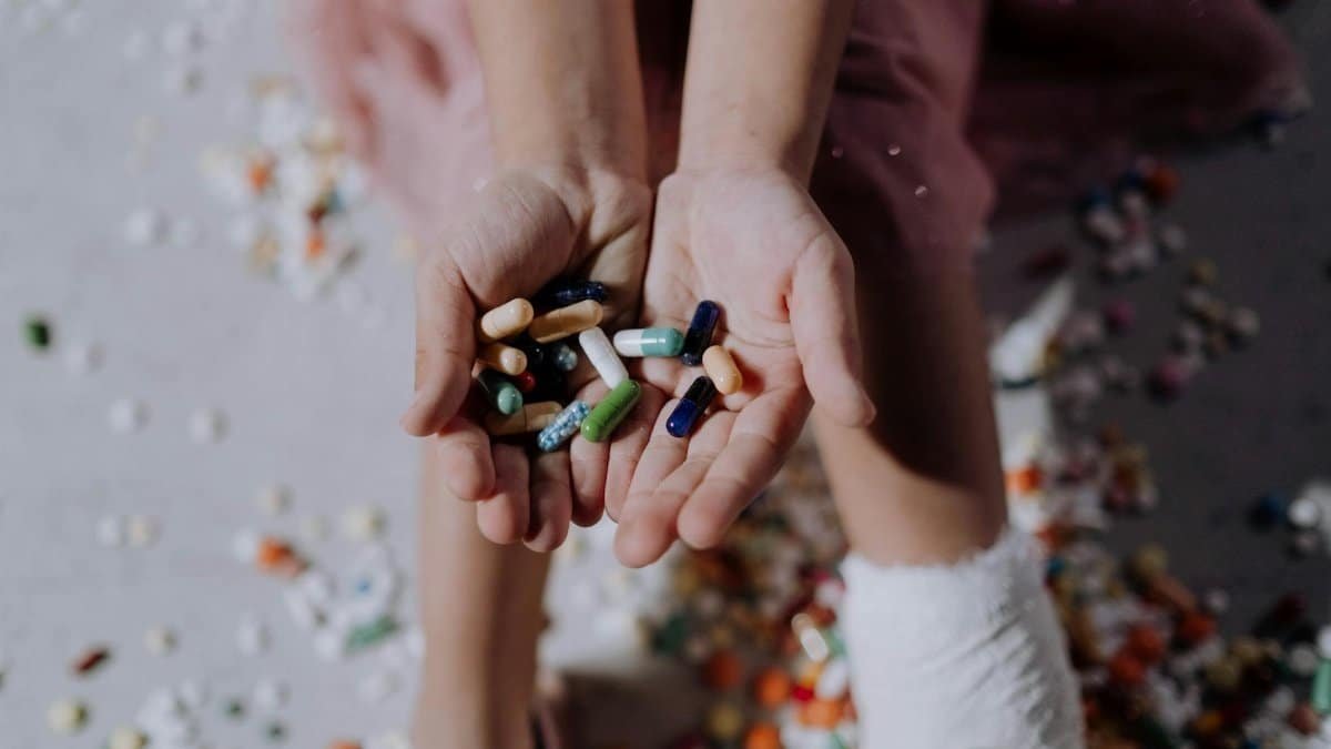 Close-up of a child holding pills with an injured leg in a cast, symbolizing health and recovery.