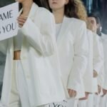 People in white outfits holding 'Same As You' signs, promoting diversity and equality.
