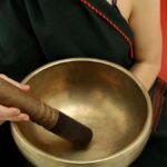 Close-up of a person holding a Tibetan singing bowl during meditation for relaxation and healing.