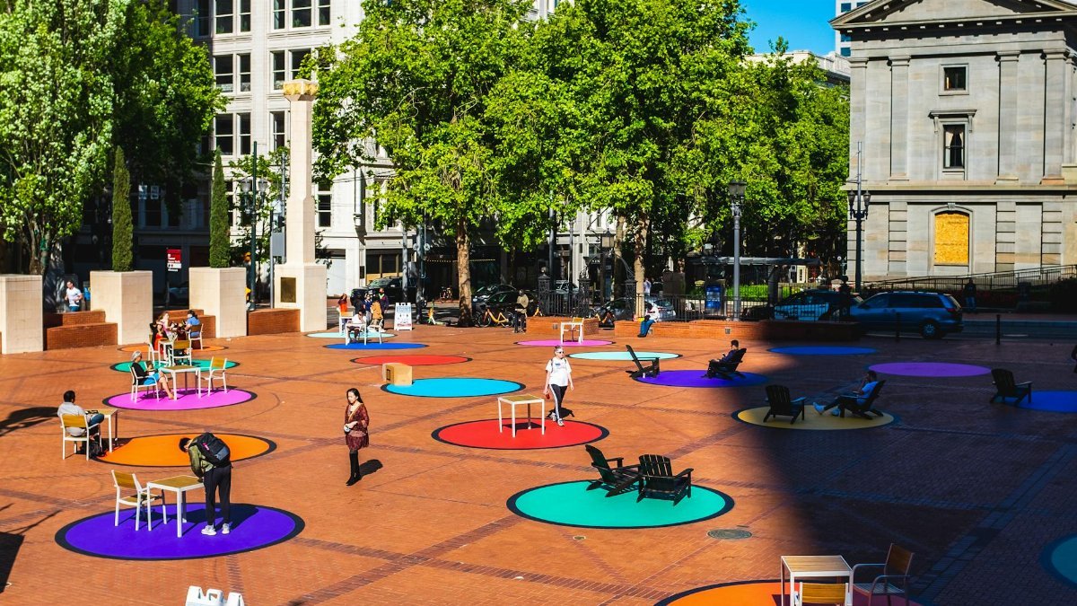 Vibrant urban plaza with colorful circles and people enjoying the outdoor seating.