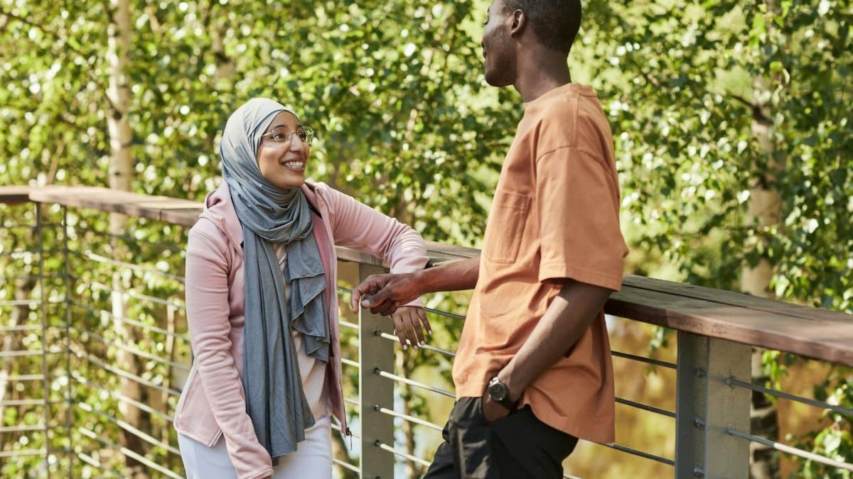 Two friends enjoying a conversation outdoors on a sunny day.