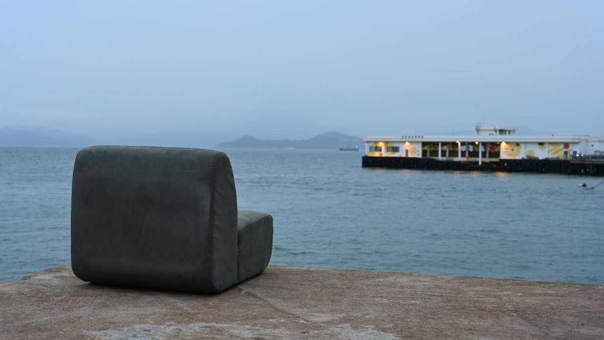 An empty chair overlooking the peaceful Hong Kong harbor during twilight, conveying solitude.