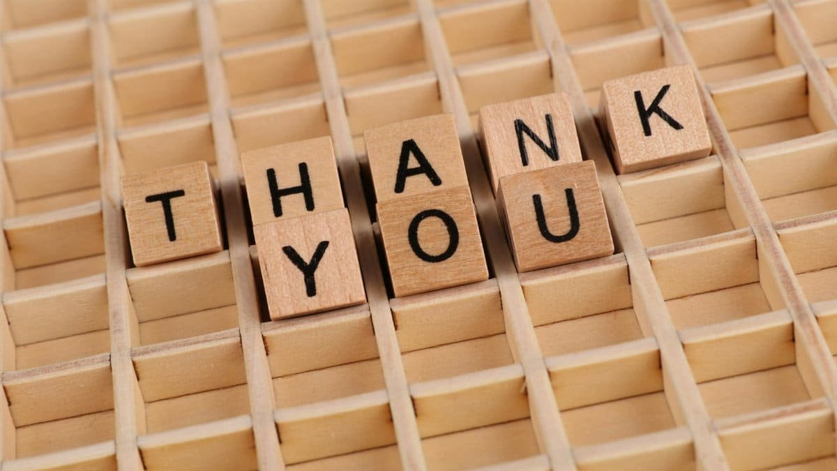 Creative arrangement of wooden blocks spelling 'Thank You' on a wooden surface.