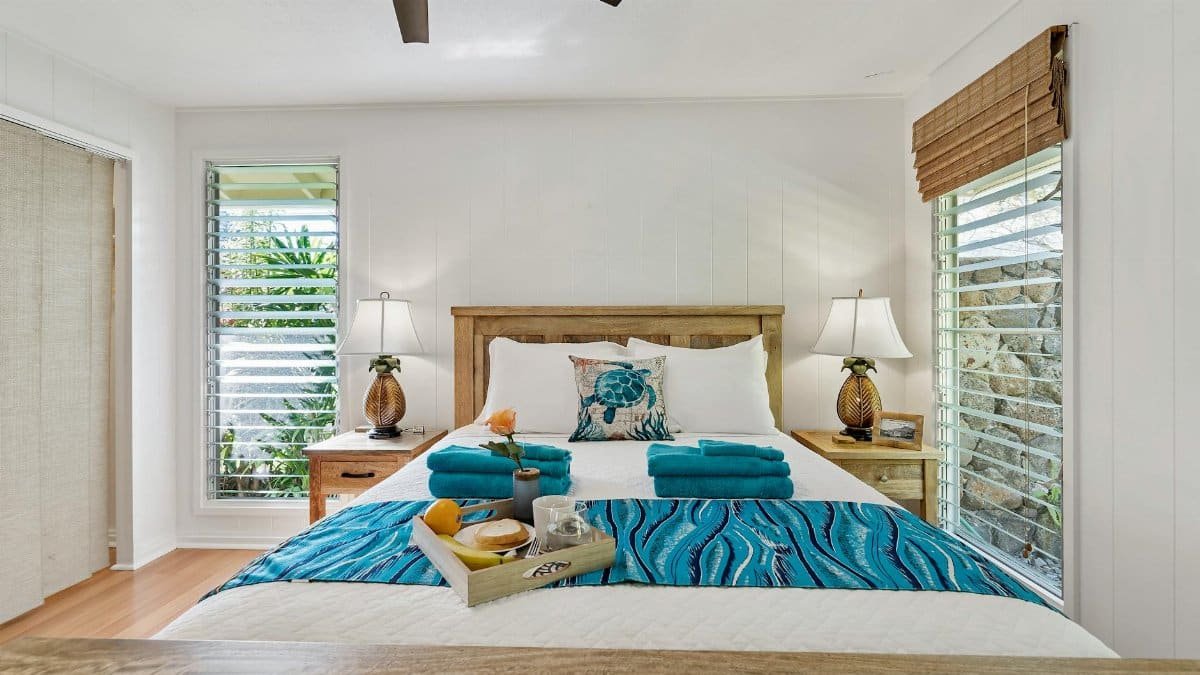 Bright bedroom interior with blue accents, natural light, and tropical decor.