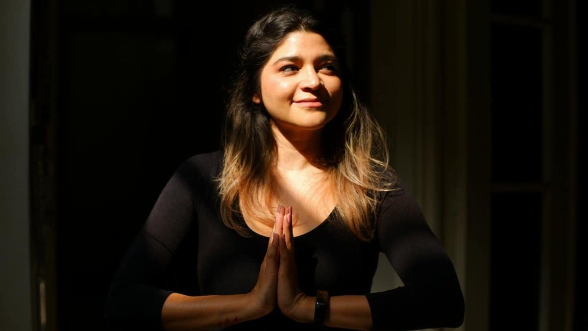 A serene woman practicing mindfulness and gratitude indoors with sunlight filtering through.