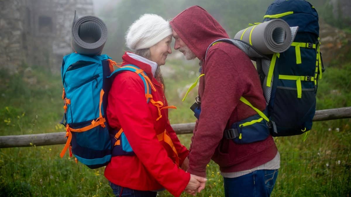 Heartwarming moment of senior couple embracing on a foggy hike in Portugal's lush countryside.