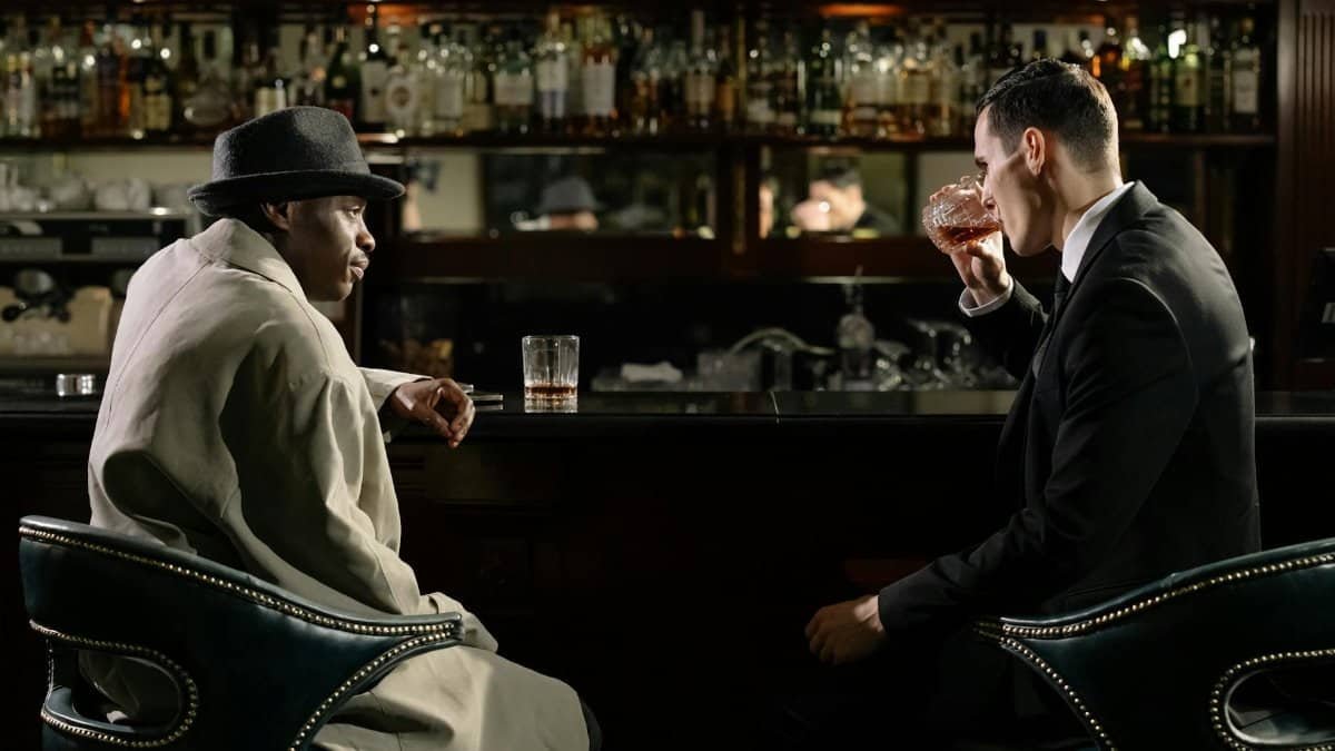 Men in a dimly lit bar engage in serious discussion over drinks.