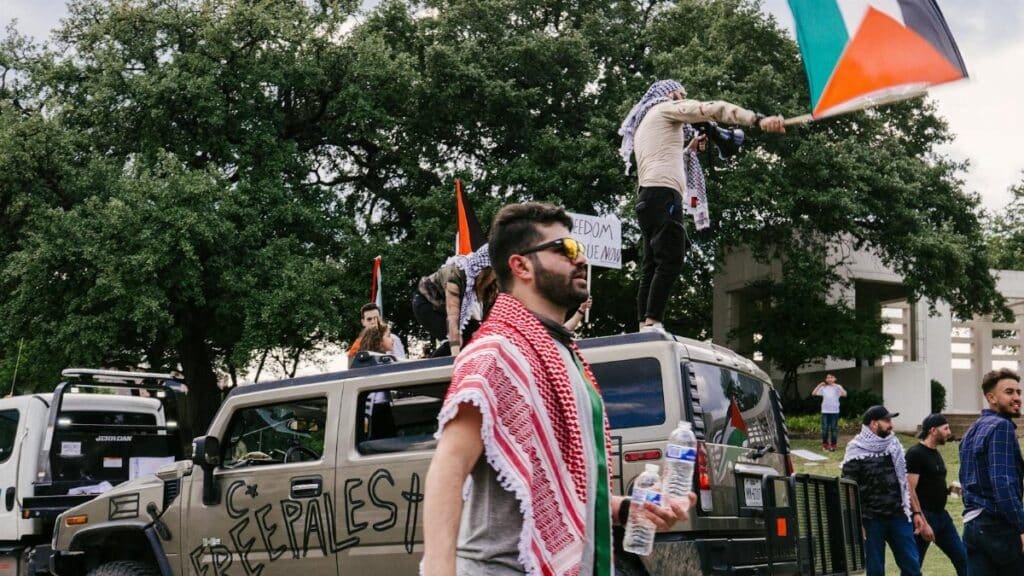 Vibrant street protest in Dallas featuring Palestinian flags and diverse crowd.