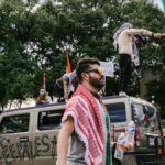 Vibrant street protest in Dallas featuring Palestinian flags and diverse crowd.