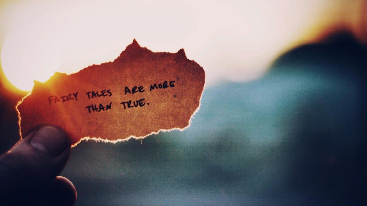 Close-up of a hand holding paper with a motivational quote at sunset, creating an inspirational mood.