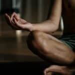 A shirtless man in a yoga studio meditating in the lotus position for relaxation and wellness.