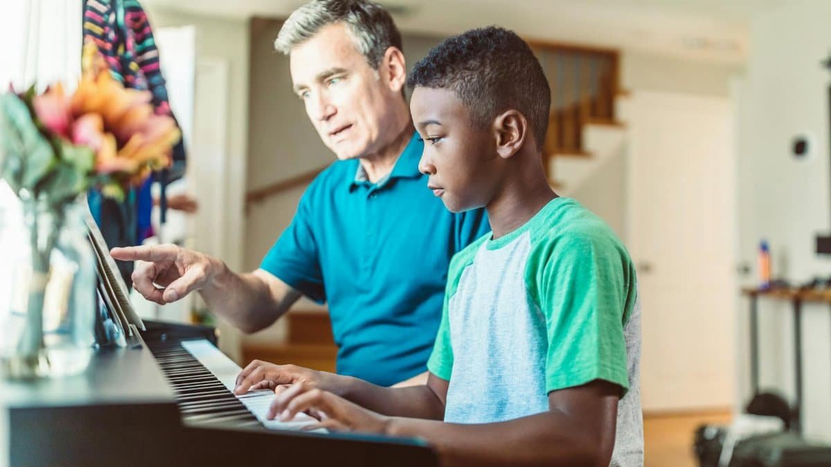 A father guides his son in learning to play the piano, fostering a love for music.