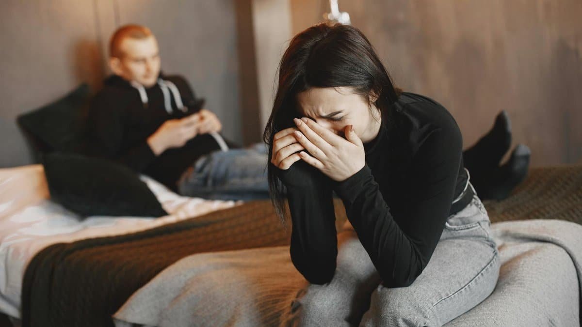 A couple experiencing tension and sadness in a modern bedroom setting.