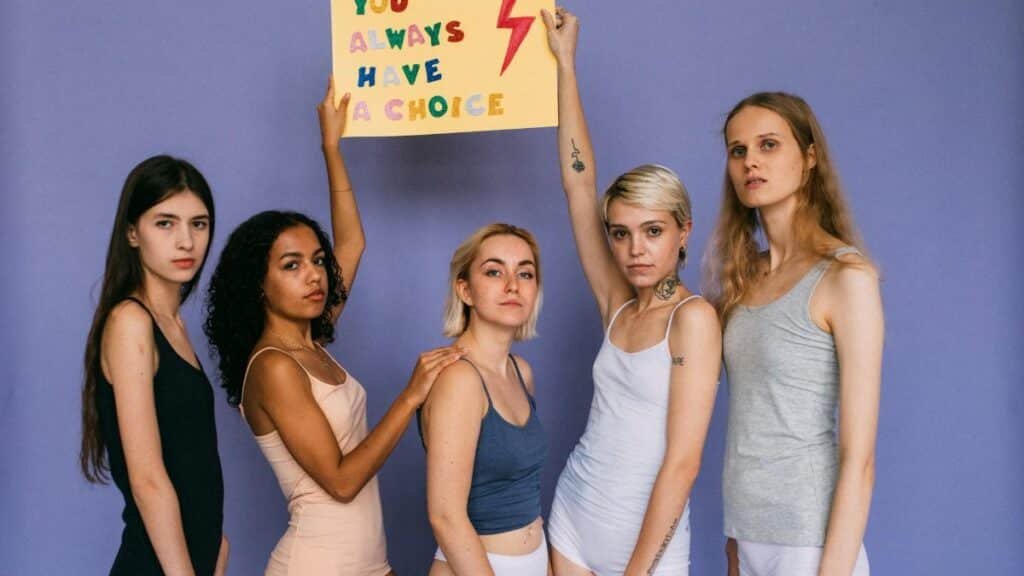 Group of diverse women standing together holding a motivational sign.
