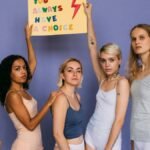 Group of diverse women standing together holding a motivational sign.