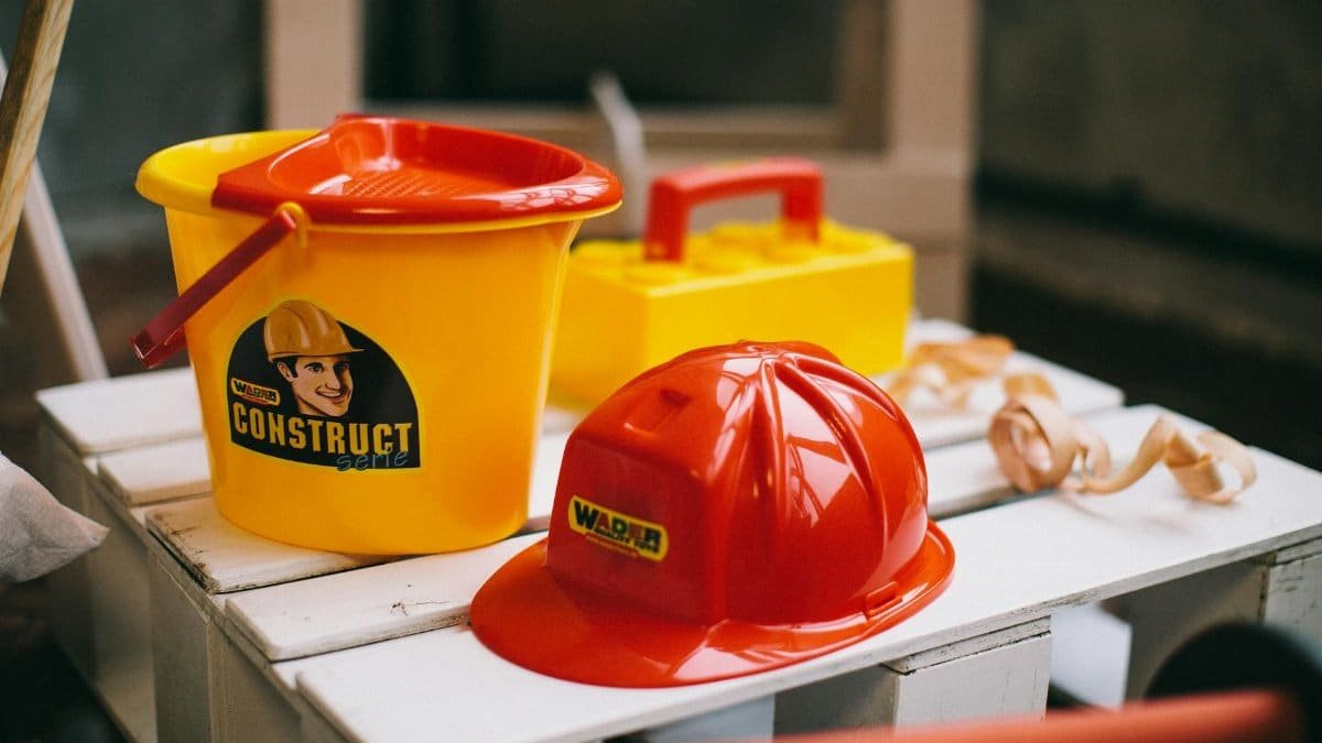 Bright toy construction set with hard hat, bucket, and toolbox on a wooden crate.
