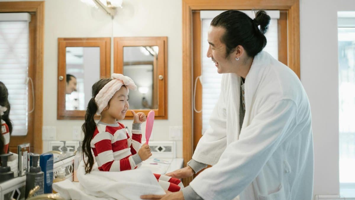 Father and daughter share a joyful morning routine, bonding in the bathroom.